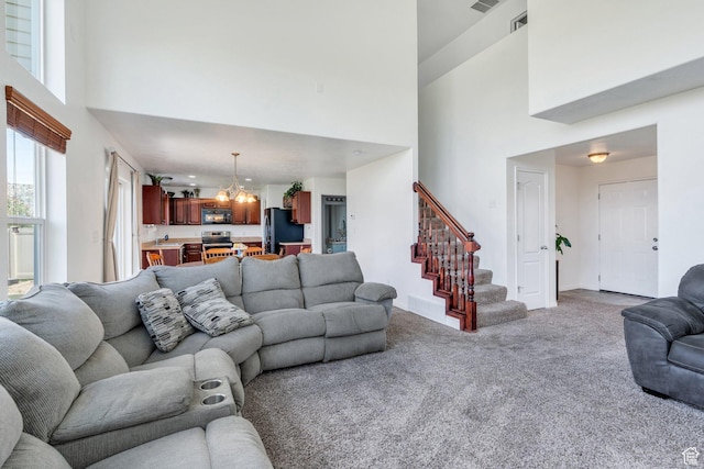 2459 E Ox Yoke Dr S, Eagle Mountain, UT 84005 - living room featuring a towering ceiling, light colored carpet, a chandelier, and stairs