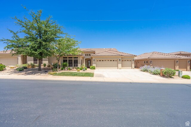 1410 W Ambassador Dr, St George, UT 84790 - mediterranean / spanish-style house featuring an attached garage, driveway, stucco siding, and a tiled roof