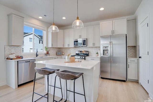 856 S 250 W, American Fork, UT 84003 - kitchen with appliances with stainless steel finishes, light wood finished floors, a kitchen bar, backsplash, and recessed lighting
