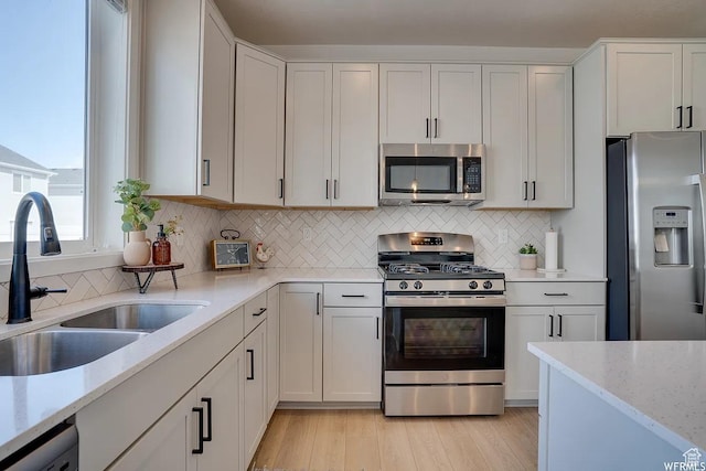 856 S 250 W, American Fork, UT 84003 - kitchen with appliances with stainless steel finishes, light stone countertops, light wood-style floors, tasteful backsplash, and white cabinetry