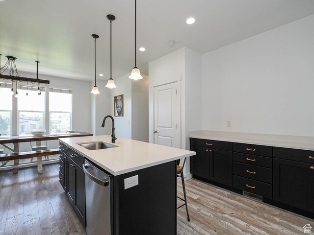 1051 W Narrows Ln S, Bluffdale, UT 84065 - kitchen featuring stainless steel dishwasher, dark cabinets, light wood finished floors, a breakfast bar area, and light countertops