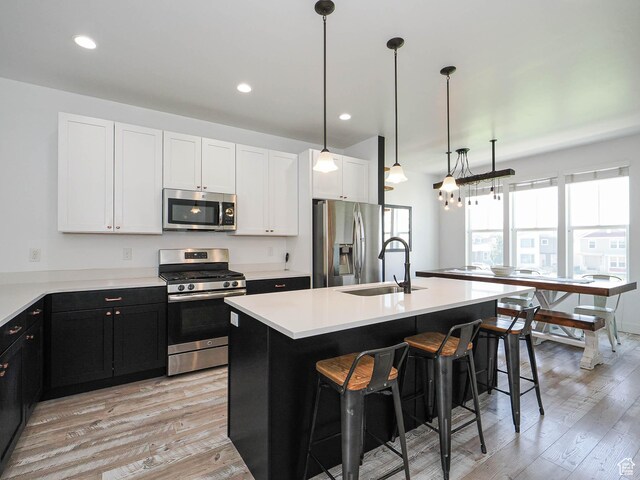 1051 W Narrows Ln S, Bluffdale, UT 84065 - kitchen featuring appliances with stainless steel finishes, a kitchen bar, light wood-style floors, dark cabinetry, and recessed lighting