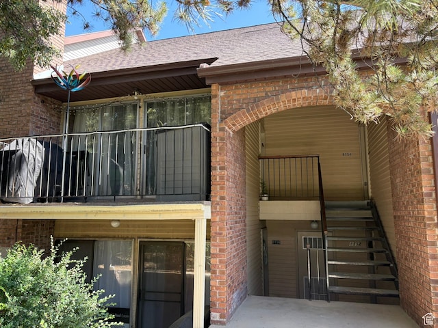 8158 S Cottonwood Hills Cir, Sandy, UT 84094 - rear view of property featuring brick siding, stairway, a shingled roof, and a balcony