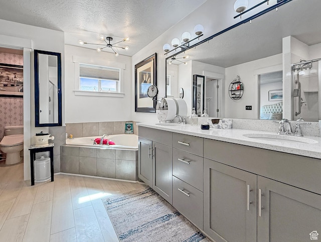 4491 Haven Rd Unit 11E, West Haven, UT 84401 - bathroom featuring double vanity, a garden tub, wood finished floors, a textured ceiling, and a chandelier