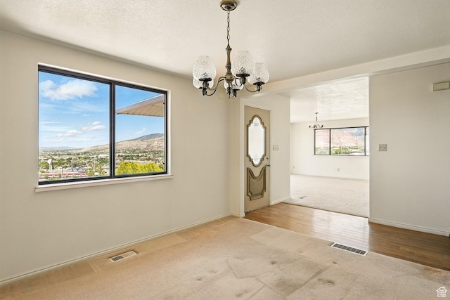 42 S Juniper Dr, Cedar City, UT 84720 - unfurnished room with a chandelier, carpet flooring, wood finished floors, and a mountain view