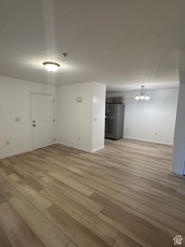 59 W Ridge Rd N, Saratoga Springs, UT 84043 - unfurnished room with light wood-style flooring, a chandelier, a pendent fire sprinkler, and a textured ceiling