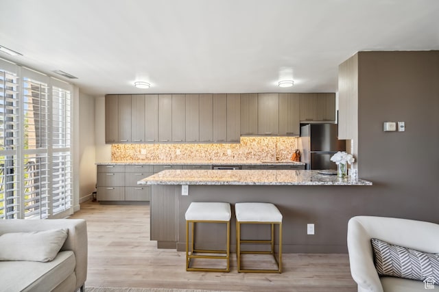 777 E S Temple N Unit 4B, Salt Lake City, UT 84102 - kitchen with freestanding refrigerator, decorative backsplash, a kitchen breakfast bar, and a peninsula