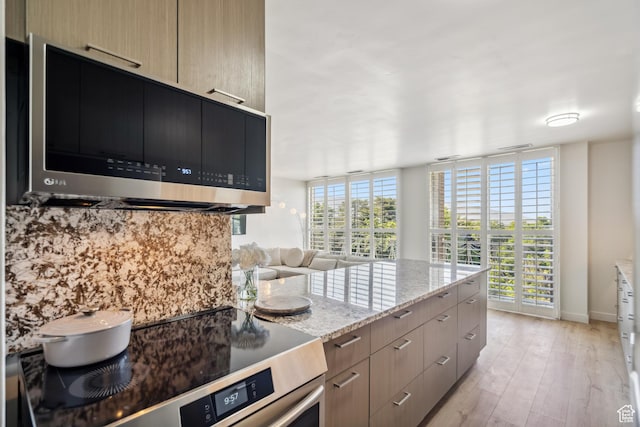 777 E S Temple N Unit 4B, Salt Lake City, UT 84102 - kitchen with stainless steel microwave, range, light stone countertops, light wood-style flooring, and modern cabinets