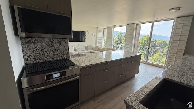 777 E S Temple N Unit 4B, Salt Lake City, UT 84102 - kitchen with stainless steel range with electric cooktop, light wood finished floors, light stone counters, expansive windows, and a peninsula