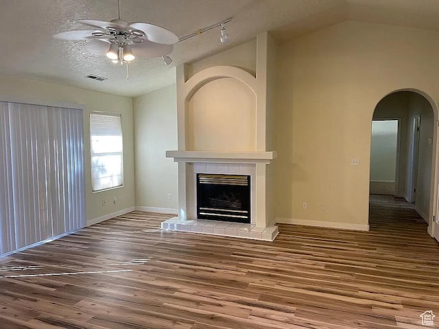 1118 E Chokeberry Dr, St George, UT 84790 - unfurnished living room with a ceiling fan, wood finished floors, a tile fireplace, arched walkways, and lofted ceiling