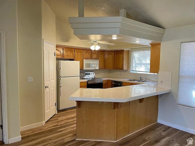 1118 E Chokeberry Dr, St George, UT 84790 - kitchen featuring white appliances, a peninsula, wood finished floors, tile countertops, and ceiling fan