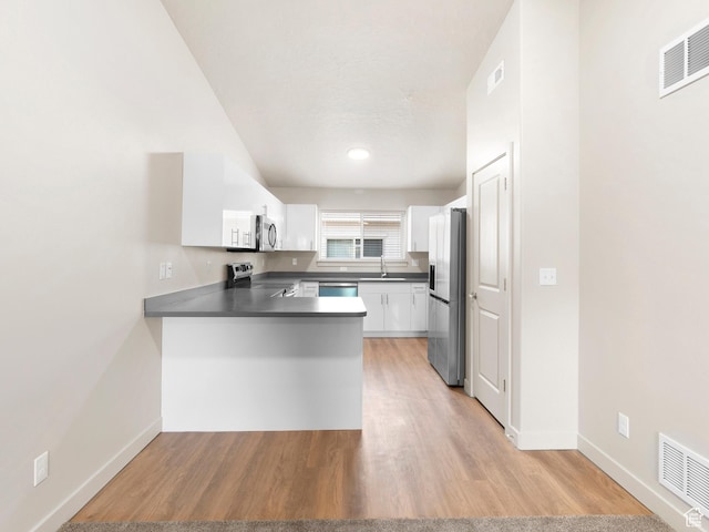 1140 W 950 N Unit C403, Orem, UT 84057 - kitchen with stainless steel appliances, a peninsula, dark countertops, white cabinets, and light wood-type flooring