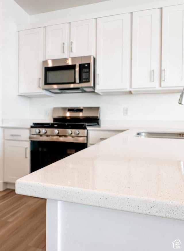 511 S 1225 W Unit 102, Logan, UT 84321 - kitchen featuring stainless steel appliances, white cabinetry, light wood-type flooring, and light stone countertops