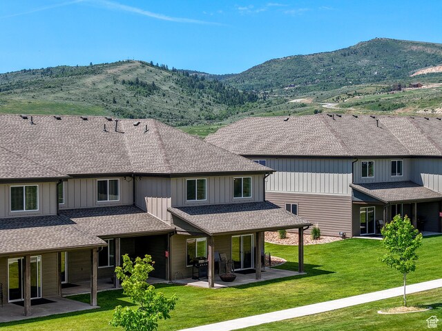 140 W 150 S Unit I34, Garden City, UT 84028 - rear view of property featuring a patio area, a mountain view, board and batten siding, a yard, and roof with shingles