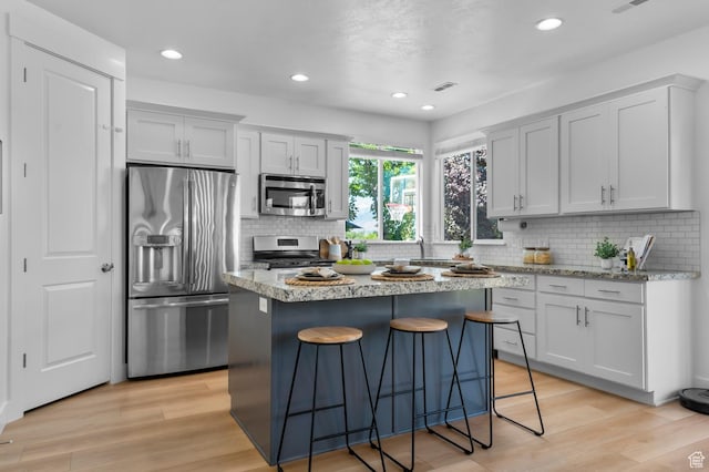 68 N Eden Way, Vineyard, UT 84059 - kitchen with stainless steel appliances, a breakfast bar area, tasteful backsplash, light wood-style floors, and recessed lighting