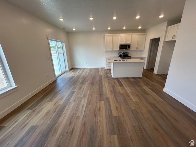 627 W 575 N Unit 545, Smithfield, UT 84335 - kitchen with stainless steel microwave, a center island with sink, white cabinetry, open floor plan, and recessed lighting