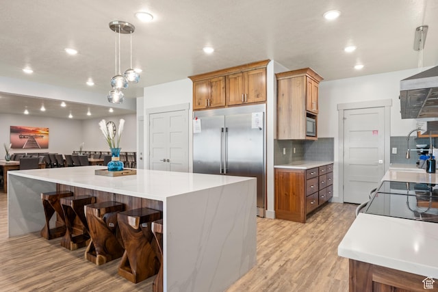 175 S Blue Topaz Ln, Garden City, UT 84028 - kitchen featuring built in appliances, light wood-type flooring, brown cabinets, backsplash, and light countertops