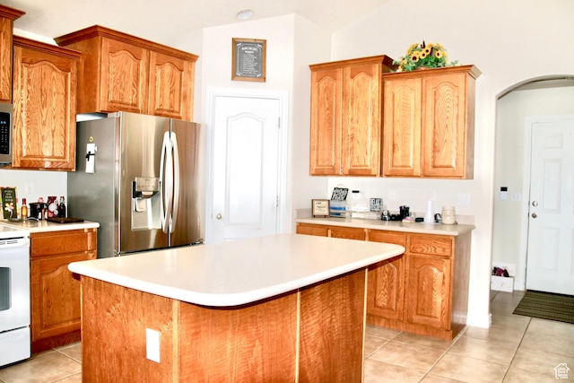 270 Amsterdam Dr, Stansbury Park, UT 84074 - kitchen with appliances with stainless steel finishes, light tile patterned floors, light countertops, a kitchen island, and arched walkways