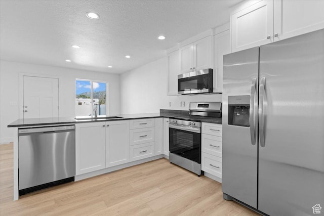 211 W 815 N Unit 19, Nephi, UT 84648 - kitchen with appliances with stainless steel finishes, a peninsula, light wood-type flooring, dark countertops, and recessed lighting