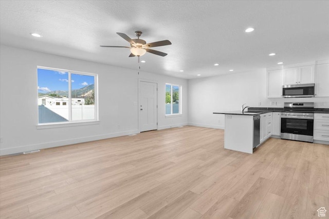 211 W 815 N Unit 19, Nephi, UT 84648 - kitchen with appliances with stainless steel finishes, open floor plan, a peninsula, dark countertops, and recessed lighting