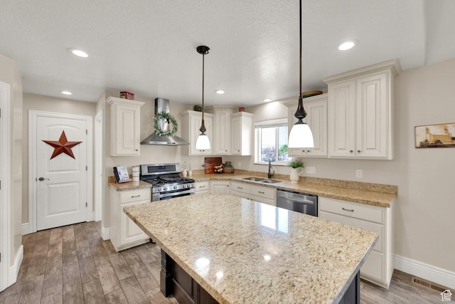 126 N Balsam Way W, Price, UT 84501 - kitchen with wall chimney exhaust hood, stainless steel appliances, light wood finished floors, hanging light fixtures, and recessed lighting