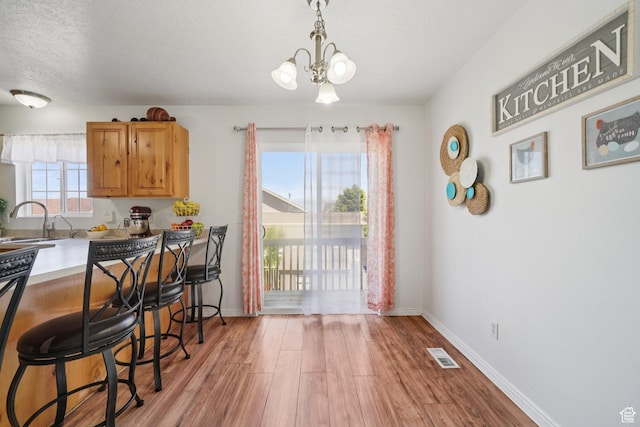 1213 E 540 N, Spanish Fork, UT 84660 - kitchen featuring light wood finished floors, a kitchen breakfast bar, a chandelier, a textured ceiling, and light countertops