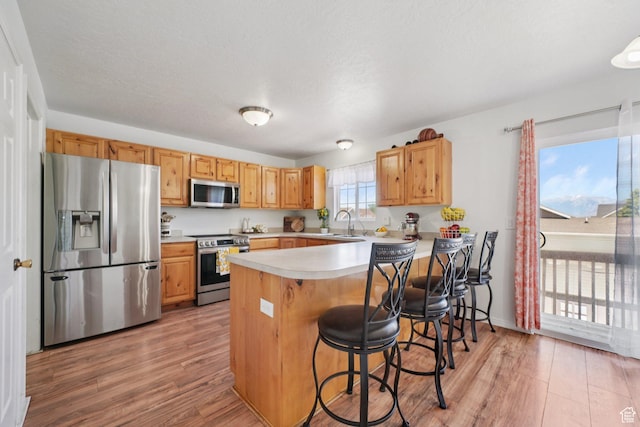 1213 E 540 N, Spanish Fork, UT 84660 - kitchen with appliances with stainless steel finishes, light wood-style floors, a peninsula, light countertops, and a kitchen bar