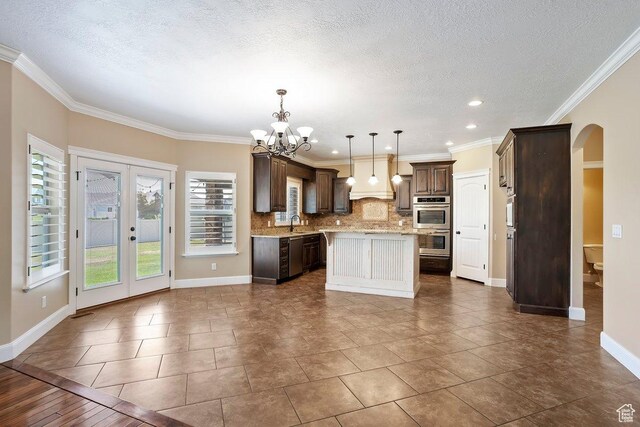 2131 S 1230 W, Syracuse, UT 84075 - kitchen featuring arched walkways, a kitchen island, a chandelier, decorative backsplash, and dark brown cabinets