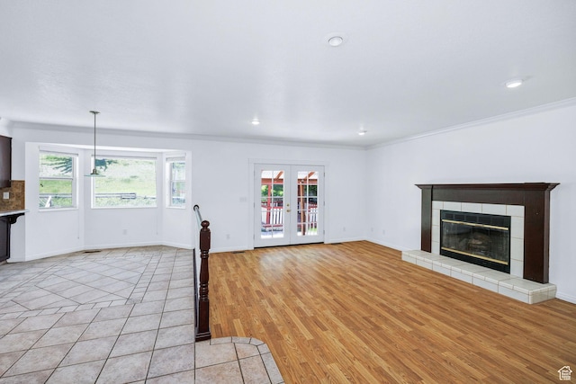 672 E Center St, Providence, UT 84332 - unfurnished living room featuring healthy amount of natural light, ornamental molding, a tiled fireplace, light wood-style flooring, and recessed lighting
