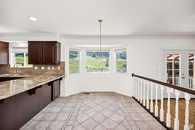 672 E Center St, Providence, UT 84332 - kitchen featuring backsplash, dark brown cabinets, light stone counters, a breakfast bar, and ornamental molding