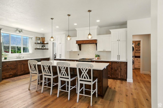 13189 N Brookside Dr, Garland, UT 84312 - kitchen featuring light countertops, a center island, decorative backsplash, white cabinets, and light wood-type flooring