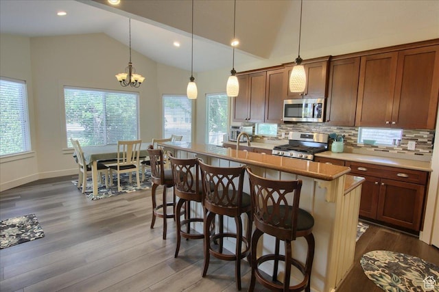 2832 S 1200 W, Syracuse, UT 84075 - kitchen featuring appliances with stainless steel finishes, dark wood-type flooring, vaulted ceiling, tasteful backsplash, and a breakfast bar area