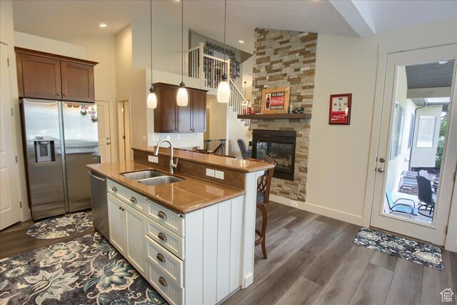 2832 S 1200 W, Syracuse, UT 84075 - kitchen featuring stainless steel appliances, dark wood-style floors, a breakfast bar, a fireplace, and a kitchen island with sink