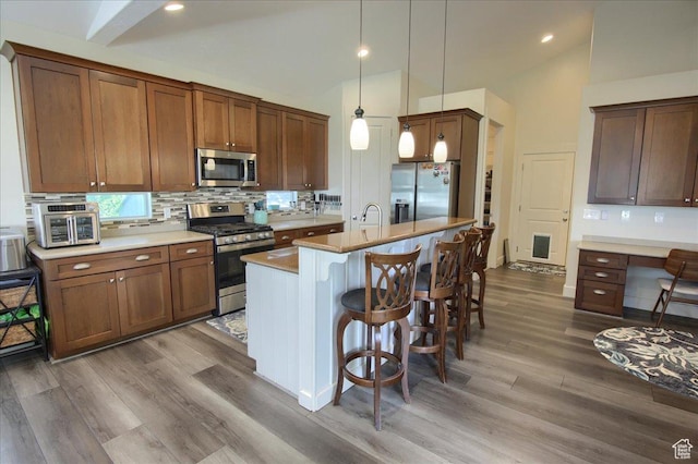 2832 S 1200 W, Syracuse, UT 84075 - kitchen featuring stainless steel appliances, vaulted ceiling, a kitchen breakfast bar, backsplash, and wood finished floors