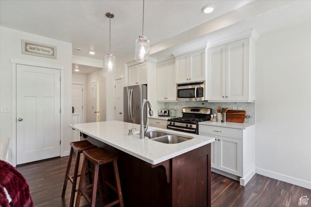 756 Spring Pond Dr, Farmington, UT 84025 - kitchen featuring appliances with stainless steel finishes, dark wood-style floors, a kitchen island with sink, backsplash, and a kitchen bar