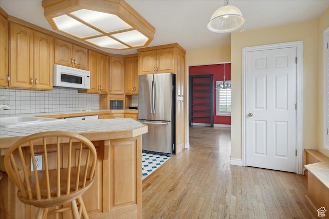 3181 E Deer Creek Cir, Cottonwood Heights, UT 84121 - kitchen with freestanding refrigerator, white microwave, tile counters, light wood-type flooring, and tasteful backsplash