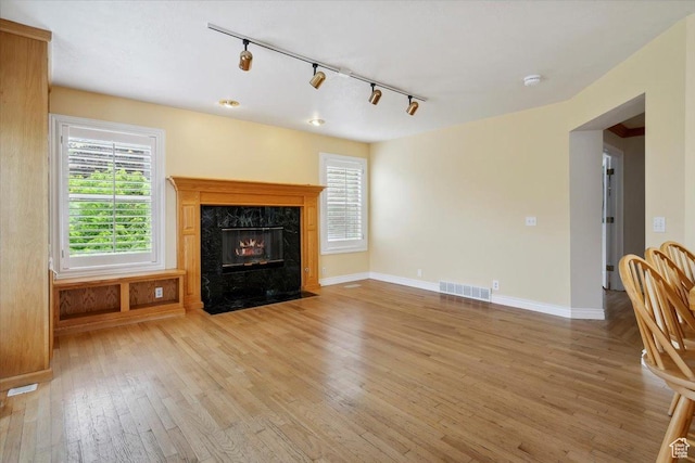 3181 E Deer Creek Cir, Cottonwood Heights, UT 84121 - unfurnished living room featuring rail lighting, light wood finished floors, healthy amount of natural light, and a high end fireplace