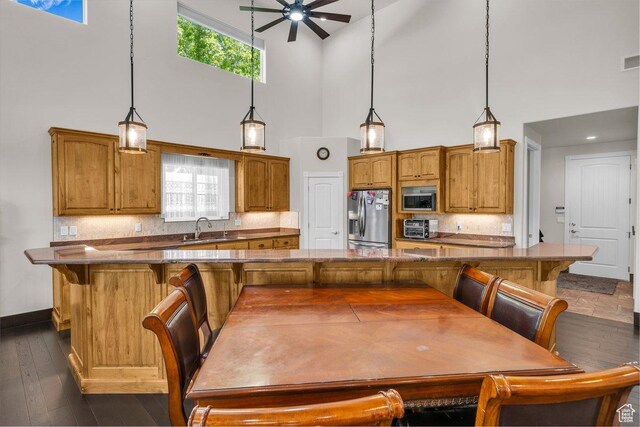 2119 Blair Cir, Santa Clara, UT 84765 - kitchen featuring stainless steel appliances, a towering ceiling, a ceiling fan, brown cabinets, and a kitchen breakfast bar