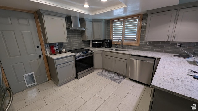 1584 E Petunia Way, Sandy, UT 84092 - kitchen featuring appliances with stainless steel finishes, wall chimney exhaust hood, gray cabinets, decorative backsplash, and a tray ceiling