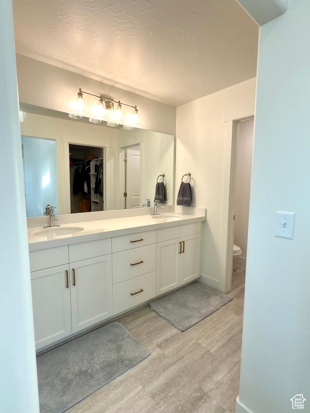 7494 N Silver Ridge Rd Unit 3466, Eagle Mountain, UT 84005 - full bathroom featuring double vanity, wood finished floors, a textured ceiling, and a spacious closet
