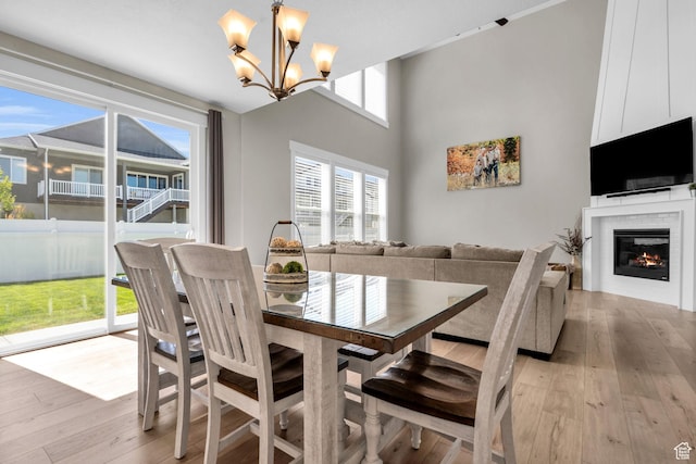 2873 S Puddle Ln, Saratoga Springs, UT 84045 - dining room featuring light wood-style floors, a chandelier, and a glass covered fireplace
