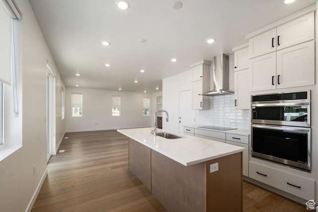 6556 S Jefferson St Unit 15, Murray, UT 84107 - kitchen with stainless steel double oven, wall chimney exhaust hood, backsplash, a center island with sink, and white cabinets