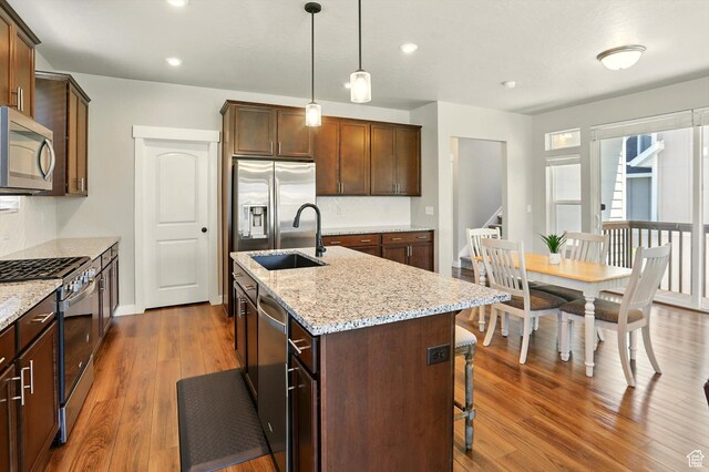 847 N 2125 W, Layton, UT 84041 - kitchen featuring stainless steel appliances, dark wood-style flooring, a center island with sink, a breakfast bar area, and light stone counters