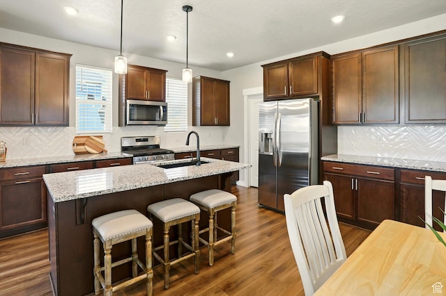 847 N 2125 W, Layton, UT 84041 - kitchen featuring appliances with stainless steel finishes, a breakfast bar area, a center island with sink, dark wood-style floors, and tasteful backsplash