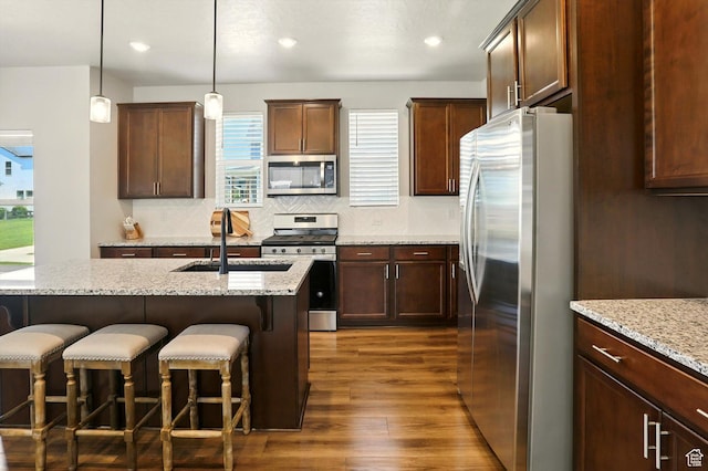 847 N 2125 W, Layton, UT 84041 - kitchen with appliances with stainless steel finishes, dark wood-style floors, a breakfast bar, decorative backsplash, and hanging light fixtures
