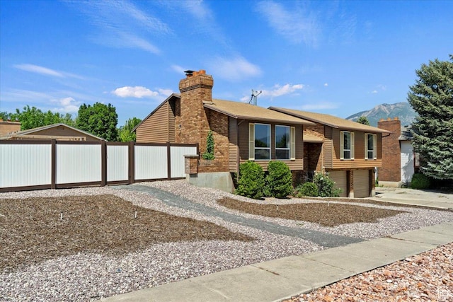 1128 W 4650 S, Riverdale, UT 84405 - view of front of home featuring concrete driveway, a chimney, a garage, and a mountain view