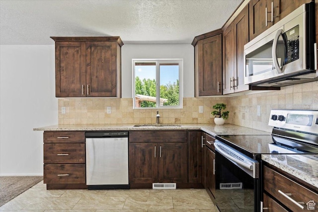 1128 W 4650 S, Riverdale, UT 84405 - kitchen with appliances with stainless steel finishes, light stone counters, a textured ceiling, tasteful backsplash, and dark brown cabinets