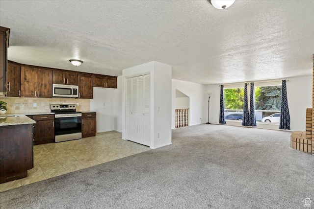 1128 W 4650 S, Riverdale, UT 84405 - kitchen with stainless steel appliances, light carpet, dark brown cabinets, open floor plan, and decorative backsplash