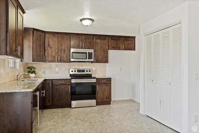 1128 W 4650 S, Riverdale, UT 84405 - kitchen featuring appliances with stainless steel finishes, decorative backsplash, dark brown cabinets, and a textured ceiling