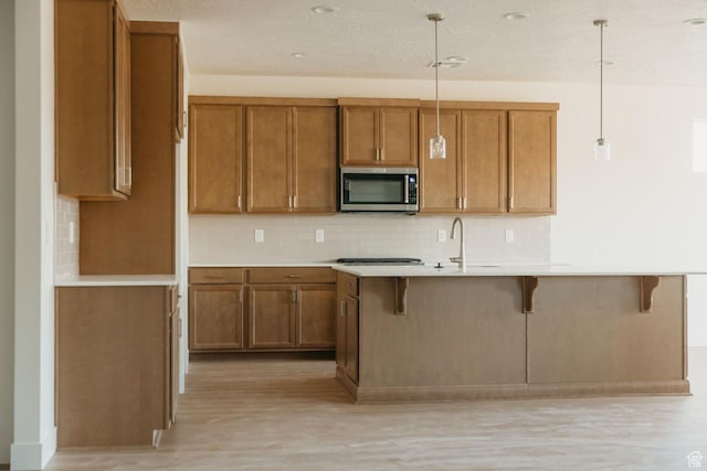 32 Rosalia Rdg, St George, UT 84770 - kitchen featuring stainless steel microwave, brown cabinets, and light wood-type flooring